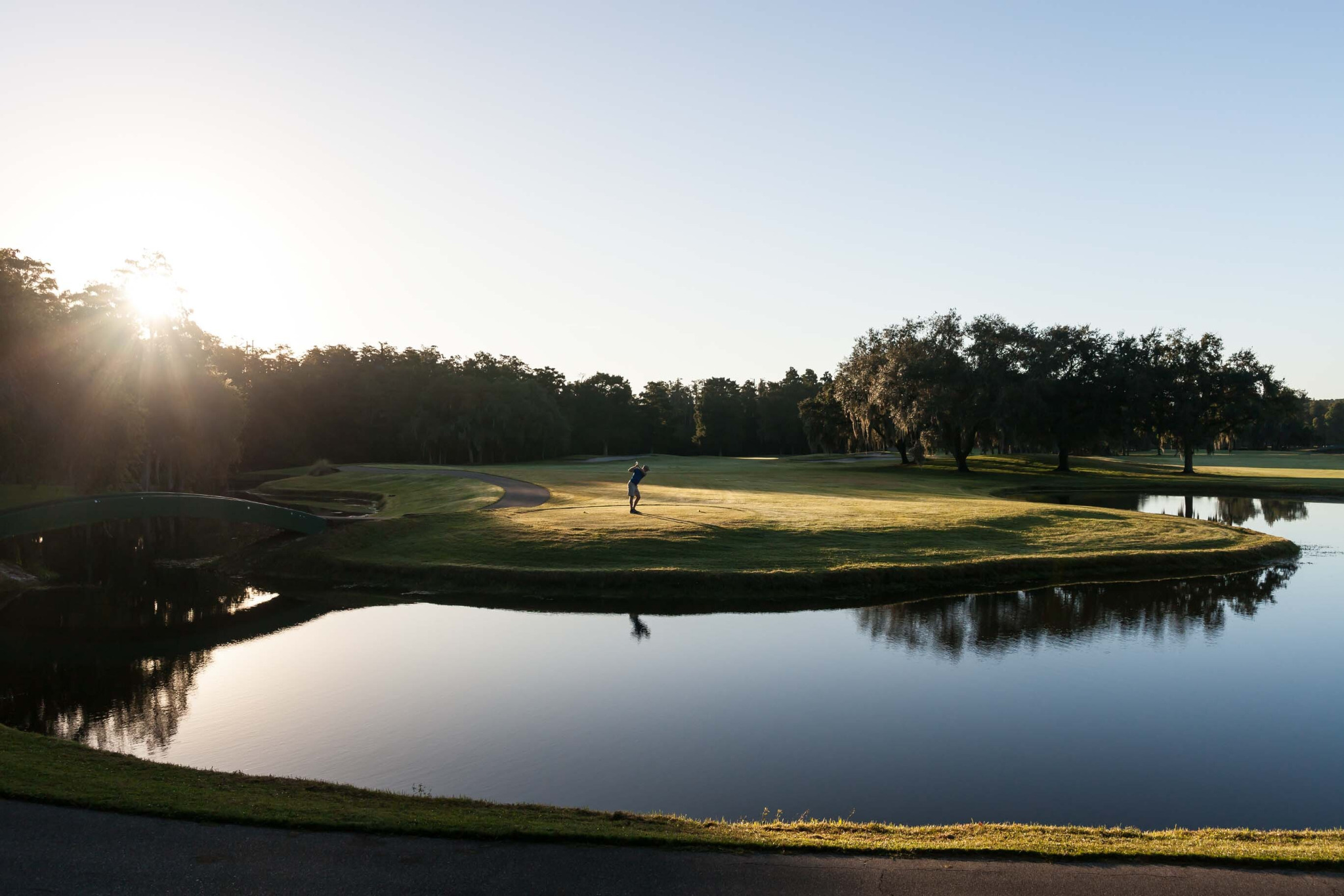 Golfer playing beside a reflective water hazard at sunrise at Innisbrook Resort